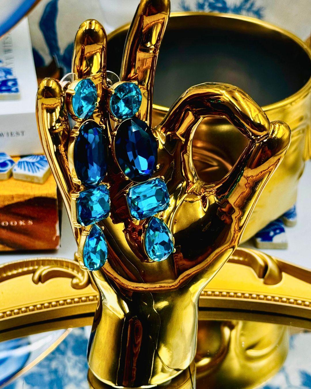 Posed view of OSCAR DE LA RENTA gold-tone blue crystal drop earrings