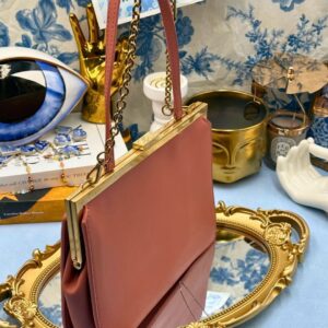 Angled view of Rosewood Pink OROTON Icon Frame Clutch