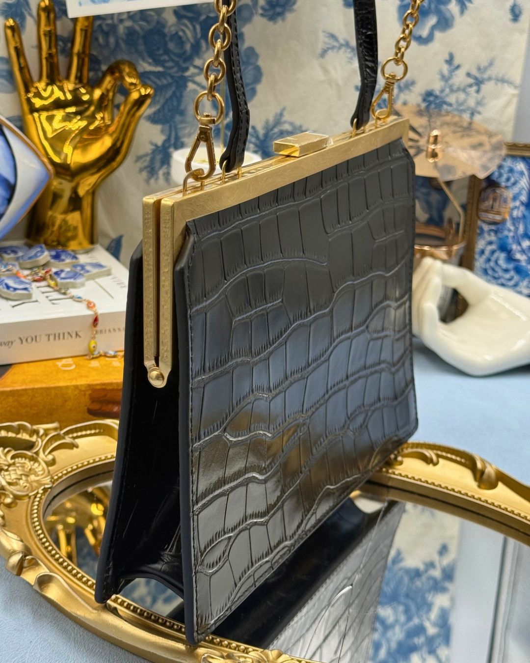 Angled view of black OROTON Icon Frame Croco Clutch