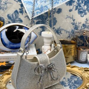 Angled view of SELF-PORTRAIT crystal-embellished crescent bow bag