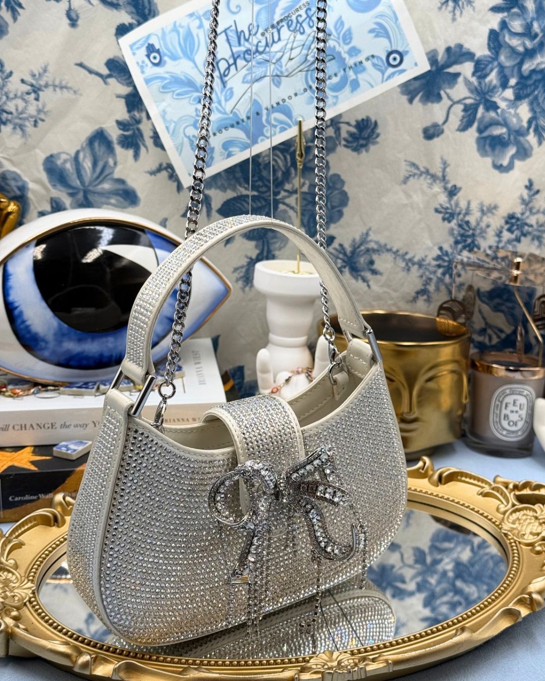 Angled view of SELF-PORTRAIT crystal-embellished crescent bow bag