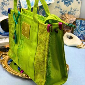 Side view of KURT GEIGER LONDON Southbank Tote Bag in lime canvas with rainbow print wide side poppers released