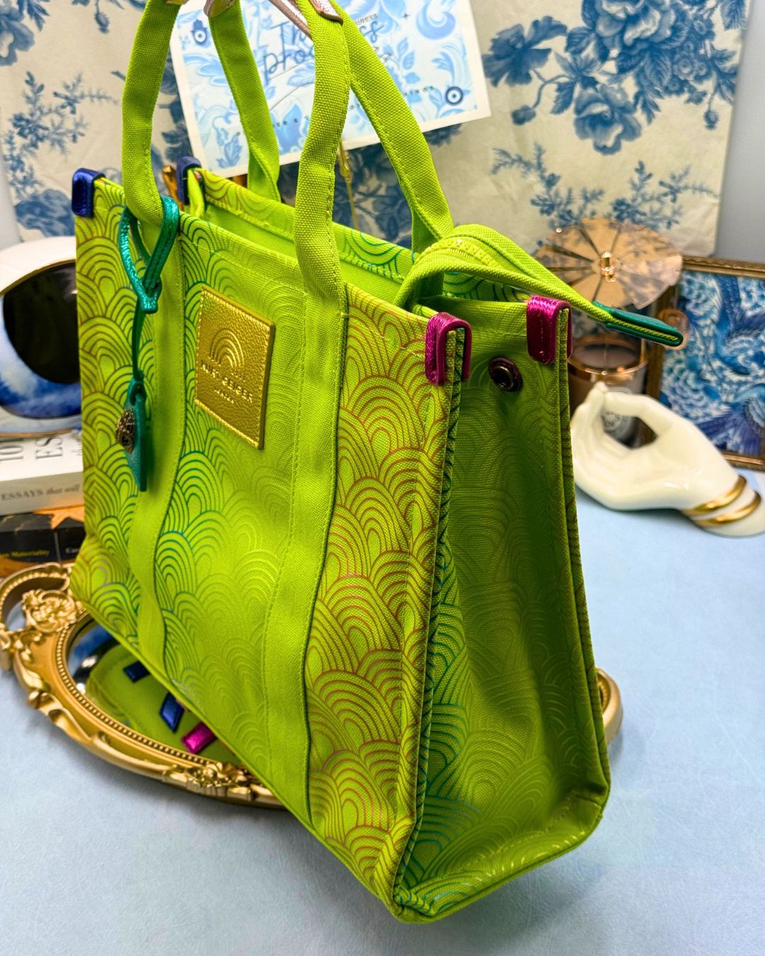 Side view of KURT GEIGER LONDON Southbank Tote Bag in lime canvas with rainbow print wide side poppers released